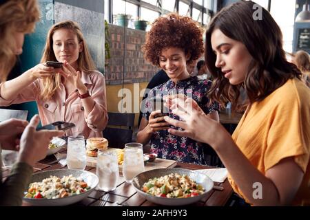 Amici di sesso femminile nel ristorante di scattare una foto di cibo nel ristorante di Post sui Social Media Foto Stock