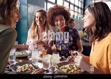 Quattro giovani amici di sesso femminile incontro per un drink e il cibo facendo un toast in Ristorante Foto Stock