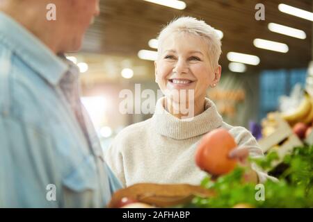Ritratto di sorridente donna senior godendo la spesa al mercato degli agricoltori con mio marito, spazio di copia Foto Stock