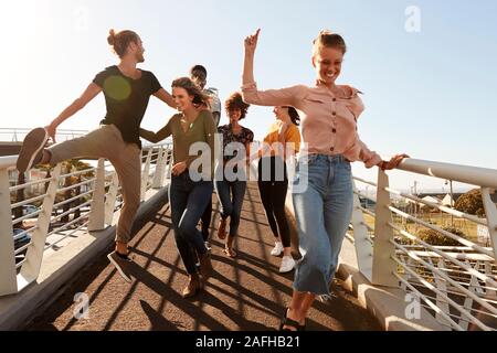 Un gruppo di giovani amici all'aperto a camminare lungo la passerella insieme Foto Stock