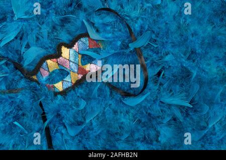 Maschera colorati visto da un angolo alto che giace tra le piume blu Foto Stock