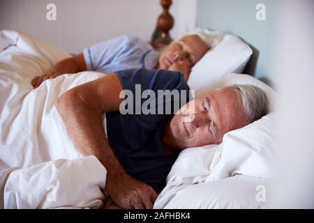 Senior bianco giovane addormentato nel loro letto, vita, close up Foto Stock