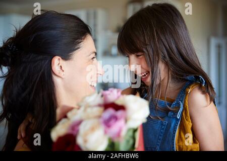 Giovane ragazza bianco dando la sua madre fiori come regalo per il suo compleanno, vicino il fuoco selettivo Foto Stock