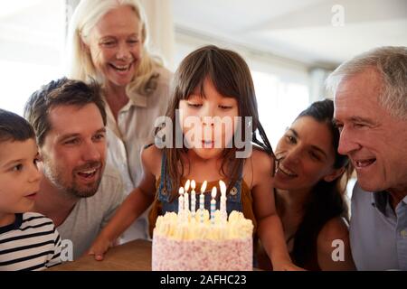 Sei anni ragazza bianco festeggia il suo compleanno con la famiglia soffiando fuori le candeline sulla torta di lei Foto Stock