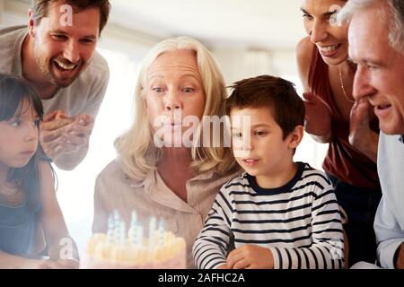 Senior donna bianca festeggia il suo compleanno con la famiglia soffiando fuori le candeline sulla torta di lei Foto Stock