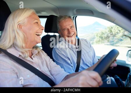 Senior donna bianca e suo marito la guida nella loro auto ridere insieme, vicino, vista laterale Foto Stock