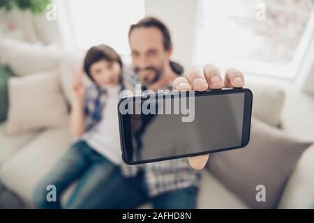 Close up foto ritratto di rilassato positivo bel lieto daddy rendendo selfie con il suo figlio più giovane sul telefono seduto sul divano comodo avere libero appoggio Foto Stock