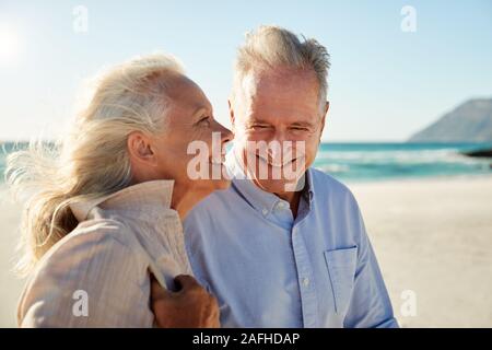 Senior bianco giovane a camminare su una spiaggia soleggiata, vita, vista laterale, vicino fino Foto Stock