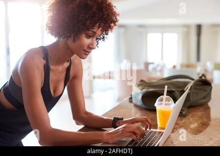 La millenaria americano africano donna controllo app fitness su laptop dopo allenamento, vista laterale Foto Stock