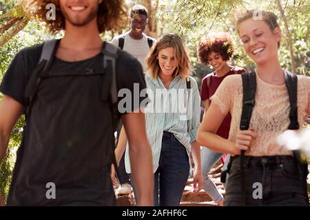 La millenaria amici escursionismo insieme in discesa su un sentiero forestale, close up, il raccolto Foto Stock