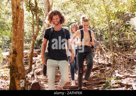 La millenaria amici escursionismo insieme in discesa su un sentiero forestale a piena lunghezza Foto Stock