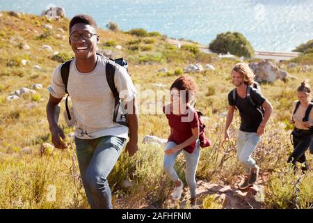 La millenaria African American uomo porta una escursione dalla costa con gli amici, sorridente alla fotocamera Foto Stock