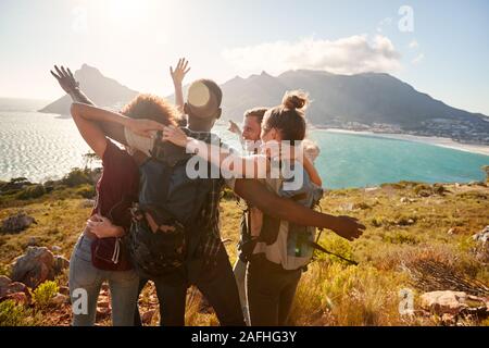 Giovani amici adulti su una escursione celebrare il raggiungimento di un vertice vicino alla costa insieme Foto Stock