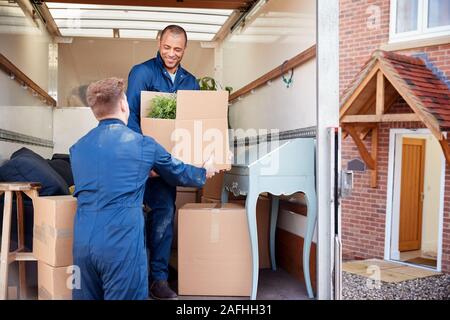 Distacco dei lavoratori della compagnia di mobili di scarico e scatole dal carrello nella nuova casa il giorno del trasloco Foto Stock