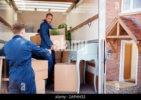 Distacco dei lavoratori della compagnia di mobili di scarico e scatole dal carrello nella nuova casa il giorno del trasloco Foto Stock