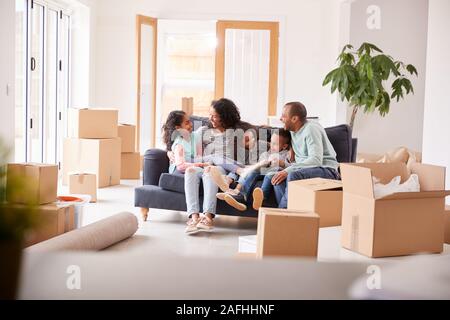 Famiglia di prendere una pausa e seduto sul divano che celebra lo spostamento nella nuova casa insieme Foto Stock