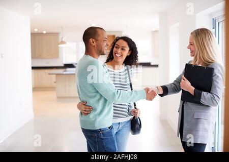 Agente immobiliare femmina stringono le mani con coppia interessati all'acquisto di casa Foto Stock
