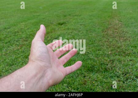 Aprire concettuale mano protesa sul prato verde. Apertura, per dare assistenza e aiutare i concetti. Foto Stock