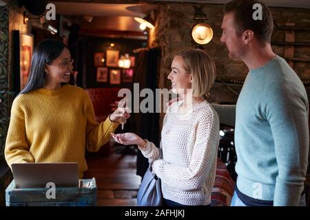 Receptionist Consegna Valutazione coppia chiave come possono controllare in Hotel Foto Stock