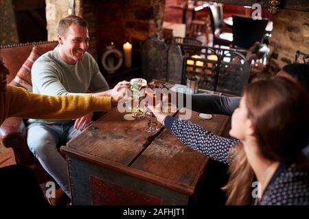 Gruppo di amici fare Toast come si incontrano per pranzo bevande nel tradizionale Pub Inglese Foto Stock