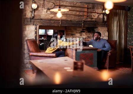 Giovane rendendo Toast come si incontrano per pranzo bevande nel tradizionale Pub Inglese Foto Stock