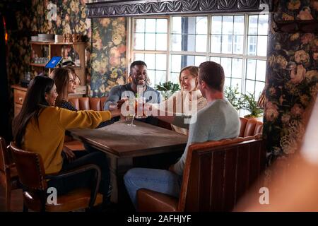 Gruppo di amici fare Toast come si incontrano per pranzo bevande nel tradizionale Pub Inglese Foto Stock