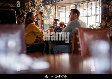 Gruppo di amici fare Toast come si incontrano per pranzo bevande nel tradizionale Pub Inglese Foto Stock