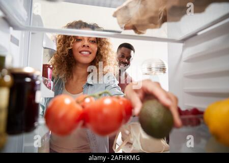 Vista dall'interno del frigorifero come giovane porta aperta e scompattare Shopping Bag di cibo Foto Stock