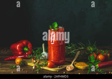 In casa naturale DIY conserve di pomodoro calda chutney di salsa al peperoncino o adjika nel vasetto di vetro in piedi sul tavolo di legno con pomodorini, sale, pepe, h Foto Stock