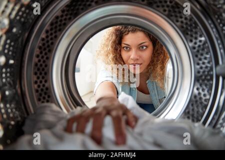 Vista dall'interno della macchina di lavaggio come donna bianco fa servizio lavanderia Foto Stock