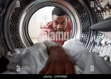 Vista dall'interno della macchina di lavaggio come uomo bianco fa servizio lavanderia Foto Stock