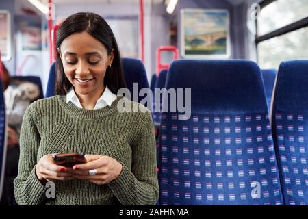 Donna seduta passeggero In treno guardando al telefono cellulare Foto Stock