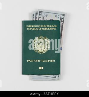 Uzbekistan passaporto con dollari americani su sfondo bianco, isolata. Vista superiore Foto Stock