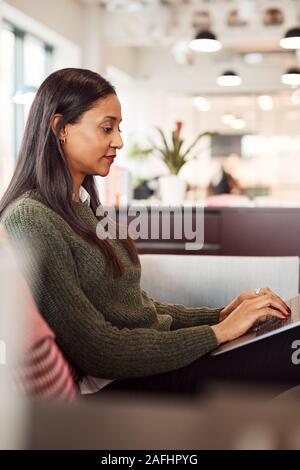 Imprenditrice seduti sul divano a lavorare sul computer portatile alla reception In Shared Workspace Office Foto Stock