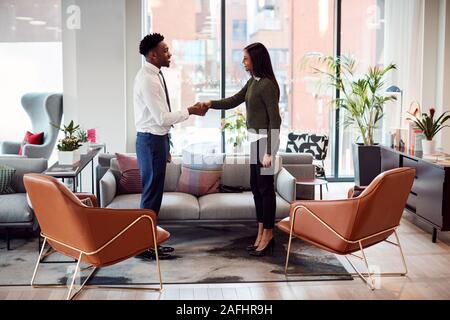 Imprenditrice stringono le mani con maschio intervista candidato in area con posti a sedere di un ufficio moderno Foto Stock