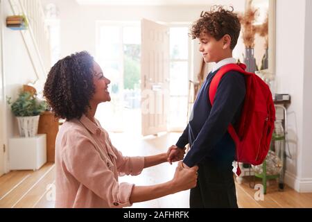 Madre Single a casa Getting figlio indossando divisa pronto per il primo giorno di scuola Foto Stock