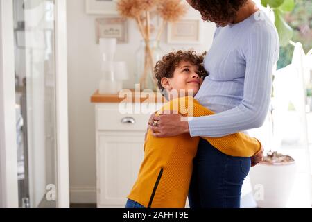 Amare il figlio dando madre abbraccio al chiuso in casa Foto Stock