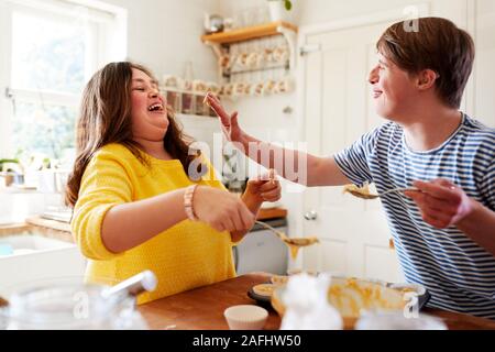 Giovani sindrome Downs giovane Divertirsi tortini di cottura nella cucina di casa Foto Stock