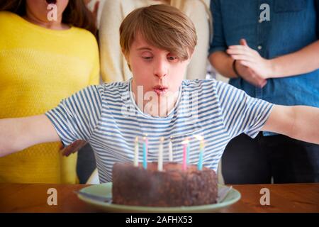 Giovani Downs uomo sindrome festeggia il compleanno a casa con torta Foto Stock