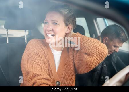 Giovane coinvolto in un incidente d'auto con conducente femmina la sofferenza con il colpo di frusta pregiudizio Foto Stock