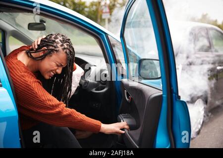 Automobilista femmina con il colpo di frusta lesioni in un incidente d'auto arrivare al di fuori del veicolo Foto Stock