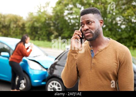Automobilista maschio coinvolto in incidente di auto chiamando compagnia di assicurazione o servizio di recupero Foto Stock
