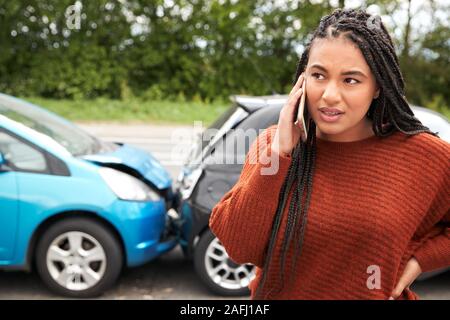 Automobilista femmina coinvolto in incidente di auto chiamando compagnia di assicurazione o servizio di recupero Foto Stock