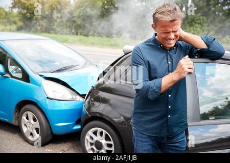 Maschio maturo automobilista con colpo di frusta lesioni in un incidente d'auto arrivare al di fuori del veicolo Foto Stock