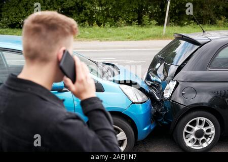 Giovane Maschio automobilista coinvolto in incidente di auto chiamando compagnia di assicurazione o servizio di recupero Foto Stock
