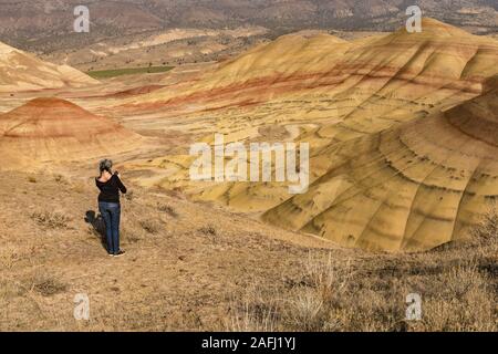 Una giovane bruna dai capelli grigi consente di scattare fotografie con il suo smartphone nel dipinto di colline si affacciano Foto Stock