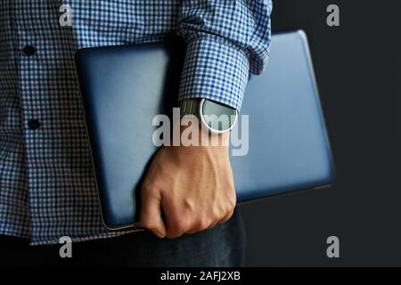 Laptop in mano. Notebook nel braccio con smartwatch. Foto Stock