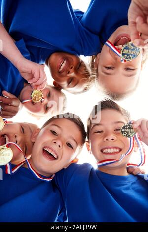 Basso angolo vista guardando in volti di bambini In Huddle sulla giornata di sport Foto Stock