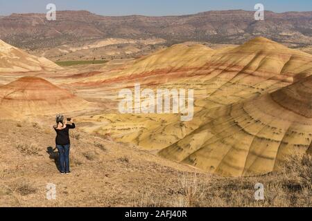 Una giovane bruna dai capelli grigi consente di scattare fotografie con il suo smartphone nel dipinto di colline si affacciano Foto Stock