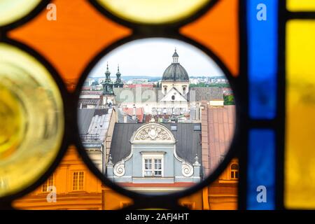 I tetti della città vecchia di Cracovia attraverso le colorate in vetro colorato dalla torre del Palazzo Comunale in un giorno d'estate. In cerchio trasparente - Chiesa di Sant'Anna Foto Stock